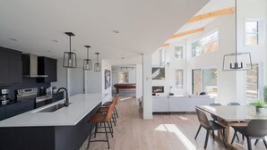 Una cocina moderna con una isla central, taburetes de bar e iluminación colgante.