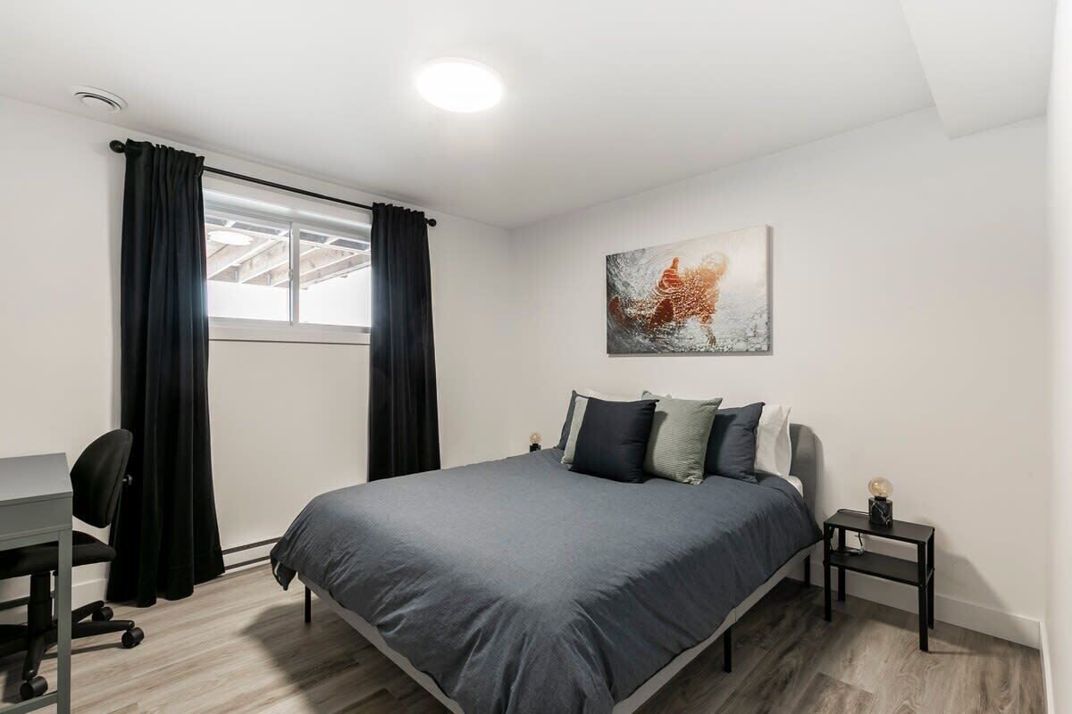 A modern bedroom with a bed, desk, and chair.