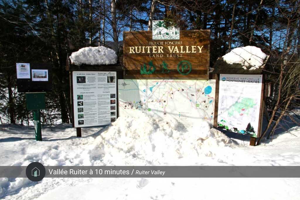 Un panneau en bois sur lequel sont inscrits les mots « Ruiter Valley » et « Land Trust », entouré de neige et d’arbres.