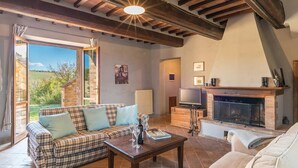A cozy living room with a sofa, a coffee table, a fireplace, and a television.
