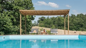 A poolside area with a pergola, two lounge chairs, and a table with a bottle and glasses.