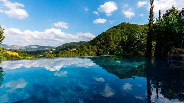 Una piscina infinita con vistas despejadas a un paisaje montañoso y un cielo claro.
