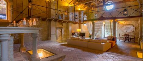 A spacious interior with a stone fireplace, a seating area with a sofa and chairs, and a dining table.