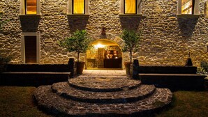 Un edificio de piedra con una entrada arqueada, plantas en macetas y una escalera de piedra circular que lleva a la puerta.