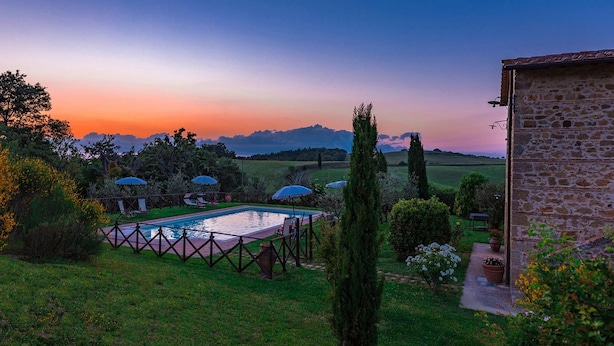 A pool area with umbrellas, a stone building, and a view of the countryside. - Si-g602-pien0at - Podere Bagnolo 8 (Pienza)