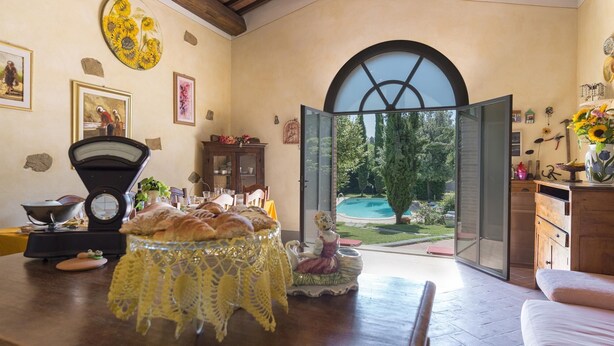 A dining area with a table set for a meal, a weighing scale, and a view of a swimming pool through an open door. - Ar-d649-foch0ar - Villa Joy 8 (Foiano della Chiana)