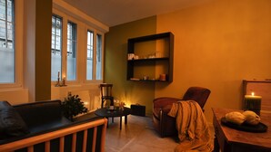 A cozy living room with a wooden bench, a red armchair, a small round table, and a bookshelf against the wall. - Apartment with sauna at the foot of the Citadel (Besançon)