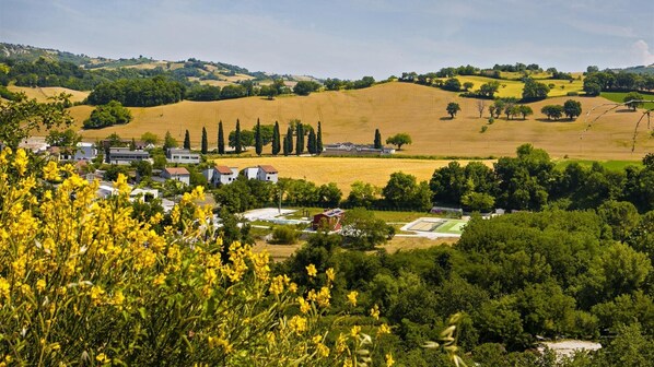 Paisaje rural con un pueblo, campos y un campo deportivo.