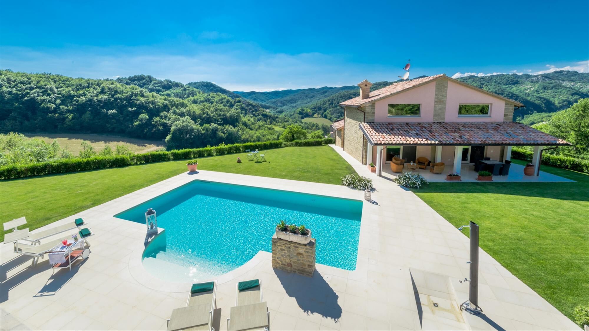 A house with a swimming pool, a patio, and a view of the surrounding hills.