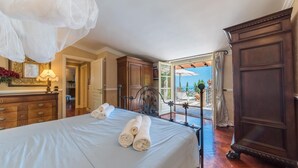 A hotel room with a bed, a wooden dresser, a mirror, and a view of the sea through an open door. - Ap-a047-cfpe10at - Fontespina 6 (Acquaviva Picena)
