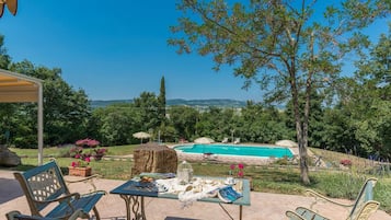 Relax by the serene pool surrounded by lush greenery and enjoy a meal at the outdoor table.