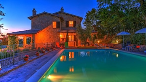 A stone house with a swimming pool, outdoor seating, and a garden.