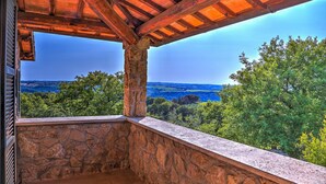 A stone balcony with a view of a lush landscape and distant hills. - Tr-a691-basc0at - Villa Poggio Verde 6 (Baschi)