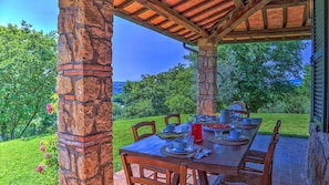 Enjoy a meal under the shade of a pergola surrounded by lush greenery.