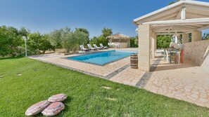 A swimming pool with lounge chairs, a pergola, and a grassy area with decorative pillows. - Ba-c134-scfa0at - Trulli Italia 6 2 (Castellana Grotte)