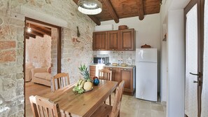 Enjoy cooking in this kitchen with a wooden dining table and exposed brick walls.