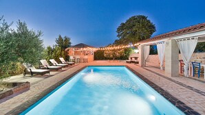 Piscina retangular com espreguiçadeiras e área de bar.