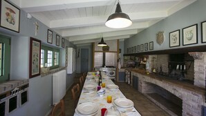 A dining area with a long table set for a meal, a brick fireplace, and various framed pictures on the walls. - Fm-l279-tspa0at - Il Podere di Fi 8 (Torre San Patrizio)