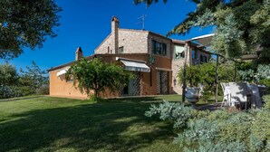 A two-story house with a brick facade, a small garden, and a dining area with outdoor furniture. - Fm-l279-tspa0at - Il Podere di Fi 8 (Torre San Patrizio)