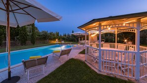 Une piscine avec des chaises longues et un kiosque.