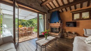 A cozy living room with a fireplace, a TV mounted on the wall, and a patio area with outdoor furniture.
