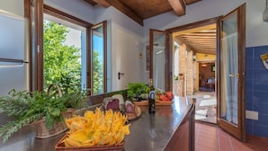 A kitchen with a wooden ceiling, a stainless steel refrigerator, and a counter with fresh produce and a bottle of olive oil. - An-f453-cbgn2at - Casale Verdicchio (Montecarotto)