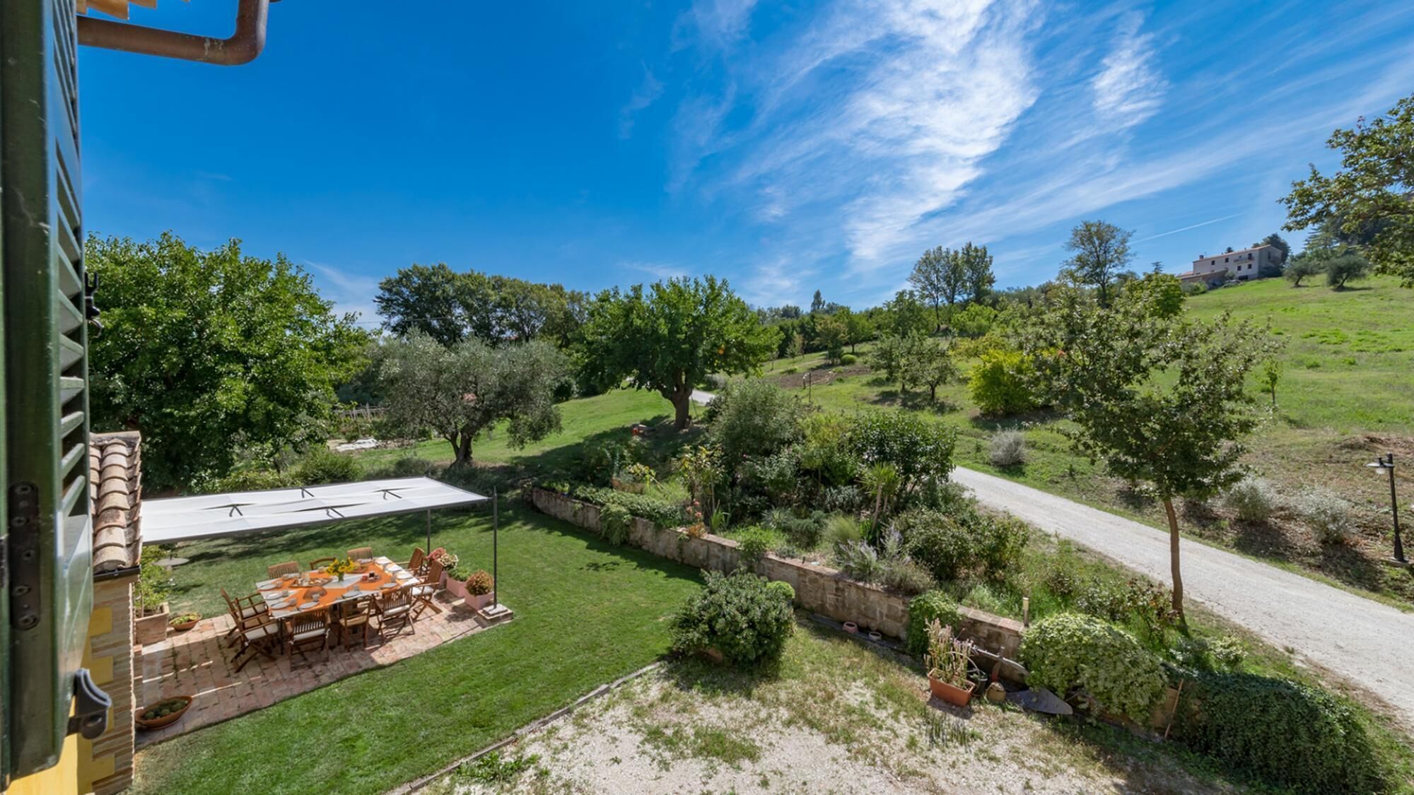 A patio with outdoor furniture and a view of a grassy landscape with trees and a road.