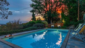 Piscina com vista para árvores e um pôr do sol.