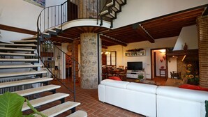 A spacious living area with a white sofa, a dining table, and a spiral staircase. - Si-i877-sp3714at - La Capanna di Franca 6 2 (Sovicille)