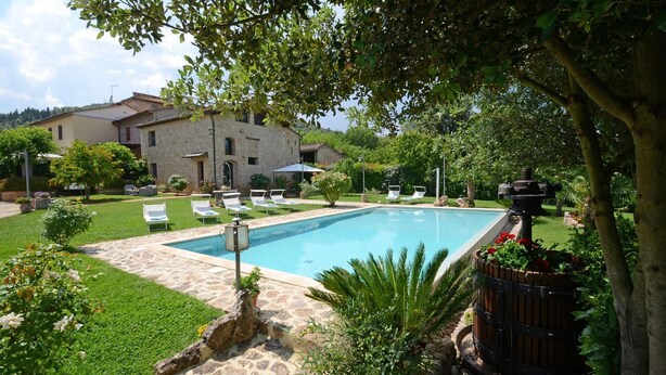 A swimming pool with lounge chairs, surrounded by greenery and a stone building in the background. - Si-i877-sp3714at - La Capanna di Franca 6 2 (Sovicille)