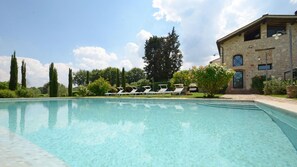 A clear swimming pool with lounge chairs and a stone building in the background. - Si-i877-sp3714at - La Capanna di Franca 6 2 (Sovicille)