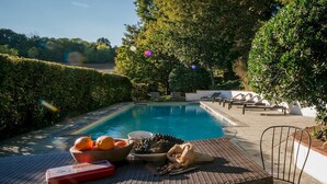 Zona de piscina con sillones de descanso, una mesa con frutas y frutos secos, y vista al mar.
