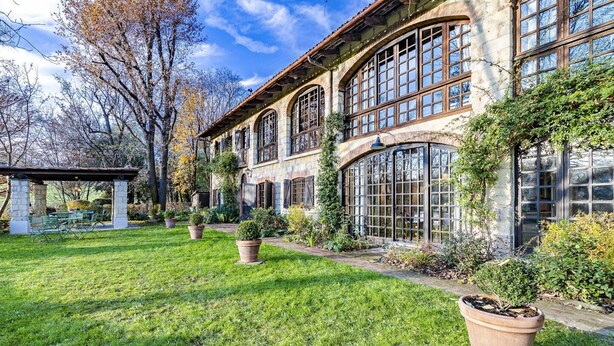 Un edificio de piedra grande con varias ventanas y un jardín bien cuidado.