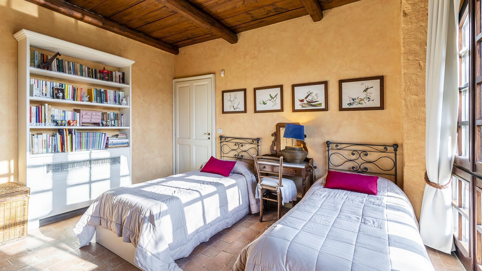 Ein Schlafzimmer mit zwei Betten, einem Bücherregal und gerahmten Kunstwerken an der Wand.