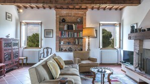 A cozy living room with a fireplace, a bookshelf, and a comfortable sofa. - Si-a468-spla0at - Fattoria L Olmo Rosso 14 (Sinalunga)
