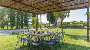 An outdoor dining area with a covered table and chairs, surrounded by trees and a view of the countryside. - Si-a468-spla0at - Fattoria L Olmo Rosso 14 (Sinalunga)