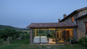 A modern house with a glass-enclosed patio, a hot tub, and a stone exterior. - Tr-i381-svim0at - Podere Pomasciano 10 (San Venanzo)