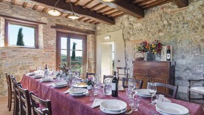 A dining area with a stone wall, wooden beams, and a table set for a meal.