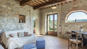 Un interno rustico in pietra con un letto, un tavolo e una vista attraverso una porta.
