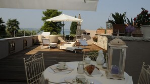 A rooftop terrace with sun loungers, a table set for tea, and potted plants. - Bs-i633-viem71a1 - Arcimboldo House 2 2 (Sirmione)