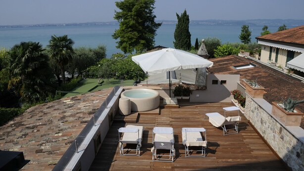 A rooftop terrace with a hot tub, lounge chairs, and a canopy umbrella overlooking a coastal view. - Bs-i633-viem71a1 - Arcimboldo House 2 2 (Sirmione)