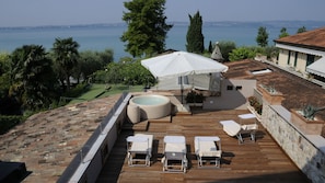 A rooftop terrace with a hot tub, lounge chairs, and a canopy umbrella overlooking a coastal view. - Bs-i633-viem71a1 - Arcimboldo House 2 2 (Sirmione)