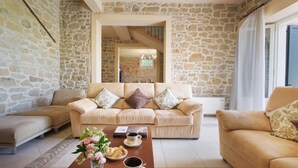 A cozy living room with a stone wall, a beige sofa set, a coffee table with flowers and snacks, and a staircase leading to an upper level. - Ar-a291-loto0at - Villa Vittoria d Anghiari 7 3 (Anghiari)