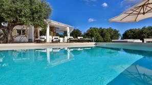 Une piscine aux eaux cristallines, dotée de chaises longues et d’une structure en forme de pergola.
