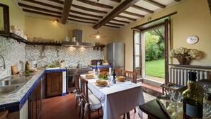 Una cocina con comedor, que cuenta con un amplio ventanal, un reloj y vistas al exterior con zonas verdes.