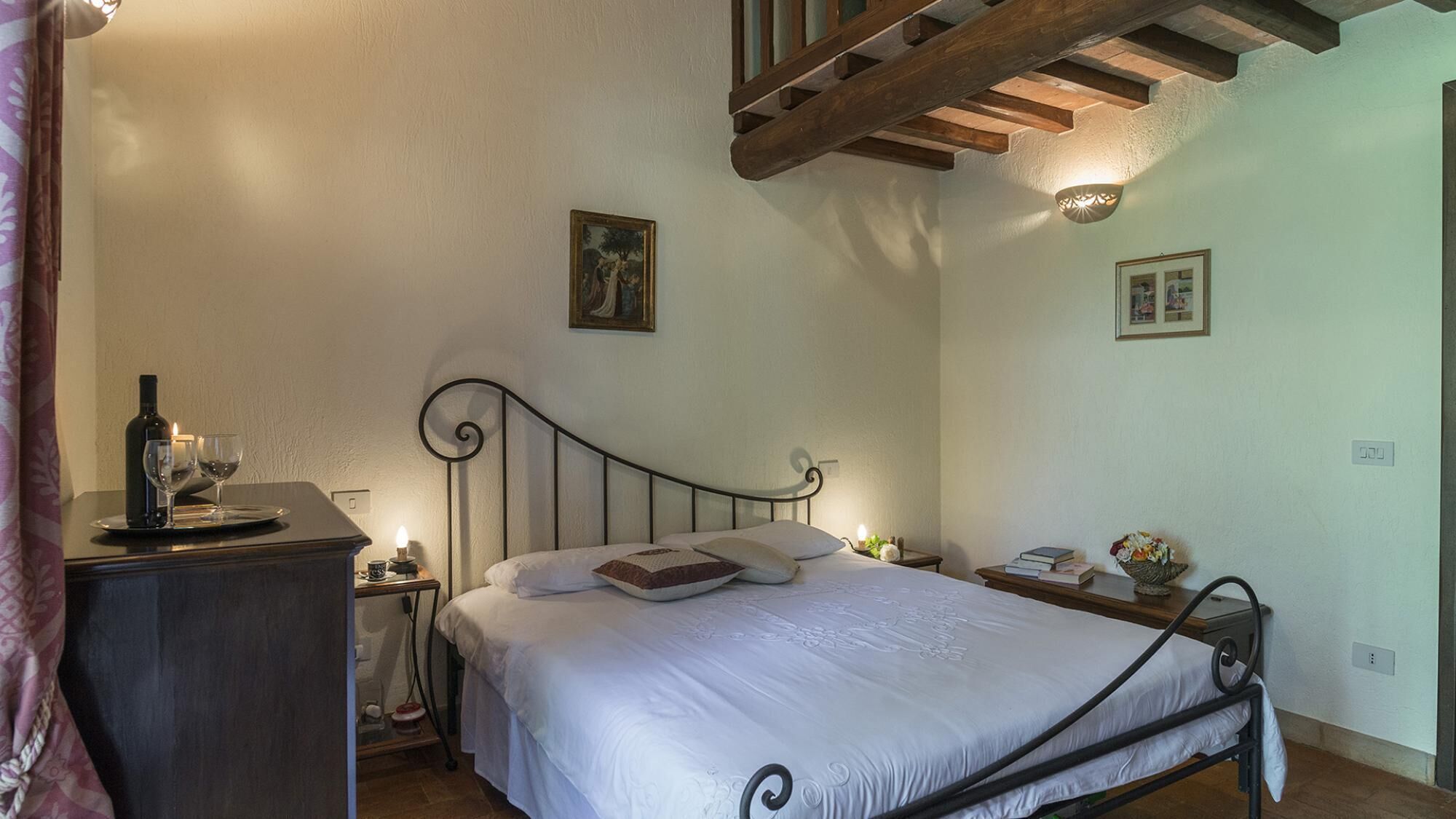 A bedroom with a bed, bedside tables, a desk, and a window.