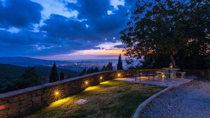 A stone bench and table set against a backdrop of a cityscape at dusk. - Ar-a390-arez0bt - Torre Ginestre 12 (Arezzo)