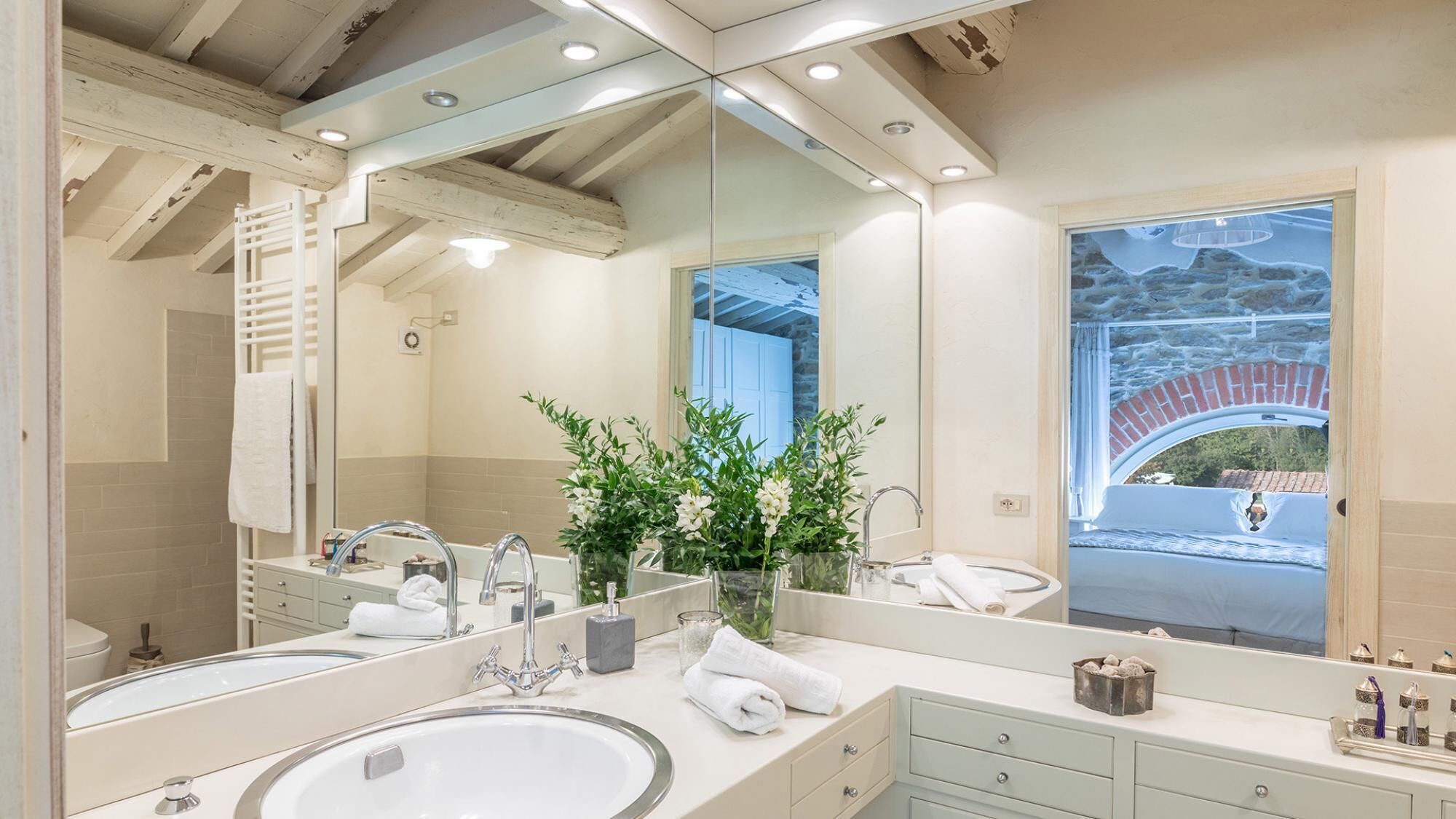 A modern bathroom with a large mirror, two sinks, and a shower.