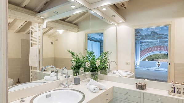 A modern bathroom with a large mirror, two sinks, and a shower.