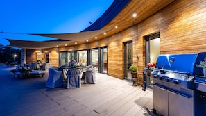 An outdoor patio with a dining area, a barbecue grill, and a covered seating area.